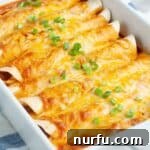 A bubbling casserole dish filled with savory ground beef enchiladas, topped with cheese and sauce.
