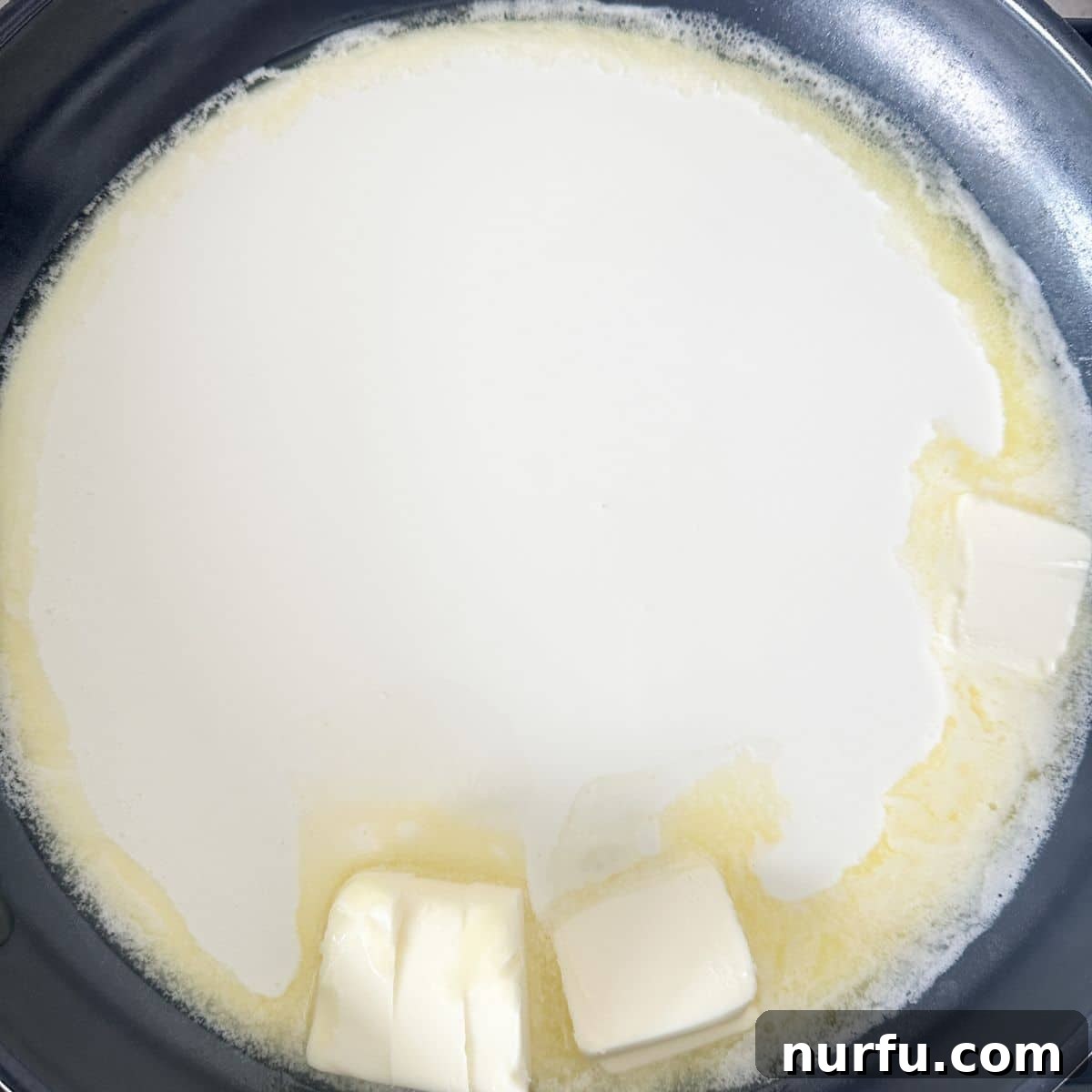 Creamy Parmesan Alfredo Spaghetti 4 A large skillet on a stovetop, showing unsalted butter cubes melting into simmering heavy cream, creating the base for the rich Alfredo sauce.
