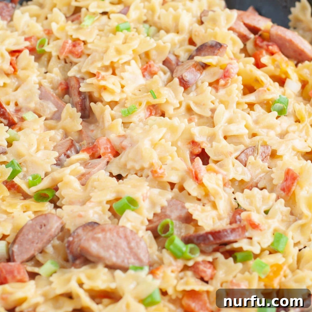 Hearty Kielbasa Pasta 7 A close-up view of the finished creamy kielbasa and pasta dish in a skillet, showcasing the rich sauce, tender pasta, and savory sausage pieces.