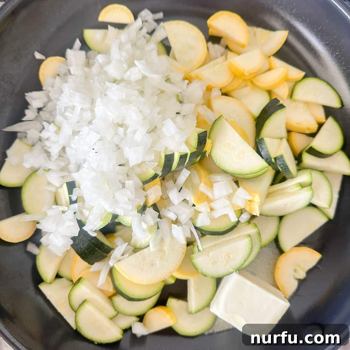 Comforting Chicken Zucchini Bake 4 A large non-stick skillet on a stovetop filled with glistening, freshly sliced zucchini, yellow squash, and diced onions, lightly sautéing in butter. The vegetables are starting to soften and release their aromatic flavors, ready for the next stage of the casserole preparation.