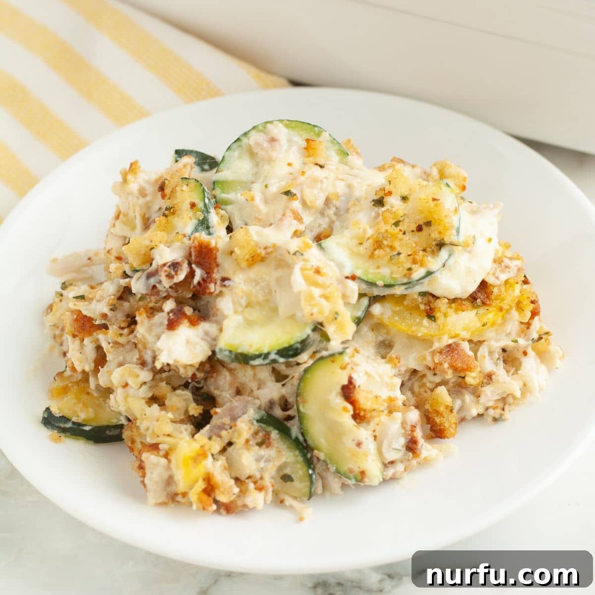 Comforting Chicken Zucchini Bake 9 A perfectly portioned plate of chicken zucchini casserole, showcasing the golden-brown stuffing topping, the creamy chicken and vegetable layers, and the vibrant colors of the squash. It's garnished simply, ready to be enjoyed as a wholesome and comforting meal.