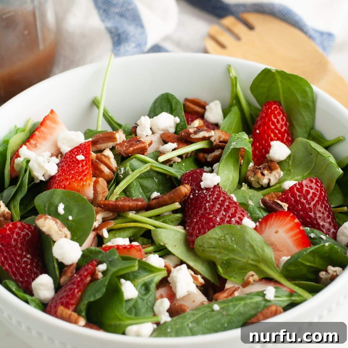 Savoring Freedom: 37 Delicious Memorial Day Recipes 24 A bowl of fresh strawberry spinach salad, featuring vibrant green spinach leaves, red strawberries, and possibly cheese or nuts.