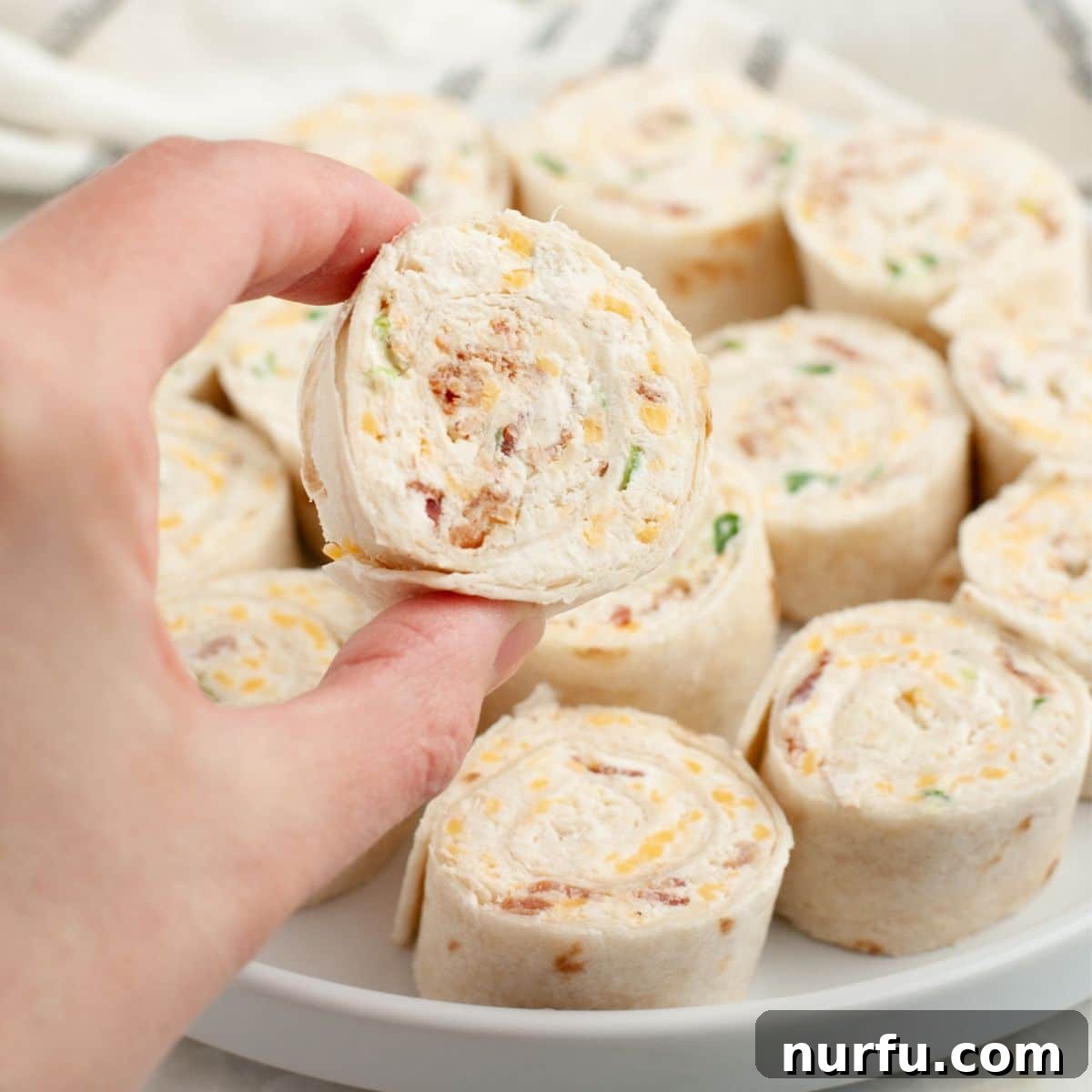 Savoring Freedom: 37 Delicious Memorial Day Recipes 5 A hand presenting a perfectly rolled crack chicken pinwheel, showcasing its layers of creamy chicken filling.