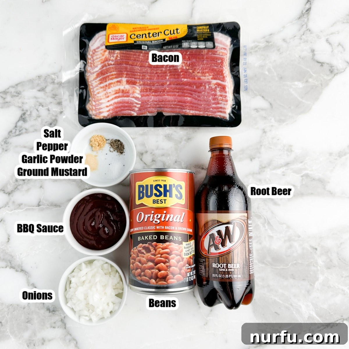 Bacon strips, root beer bottle, canned beans, seasonings, BBQ sauce, and diced onion laid out as ingredients.