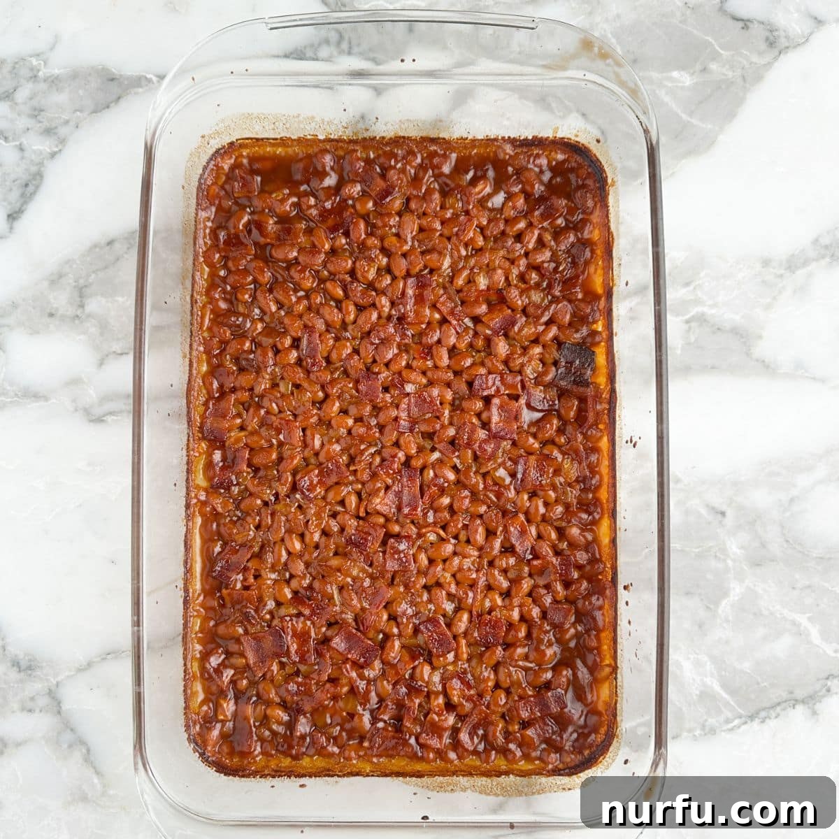 Baked beans bubbling in a casserole dish after baking, ready to serve.