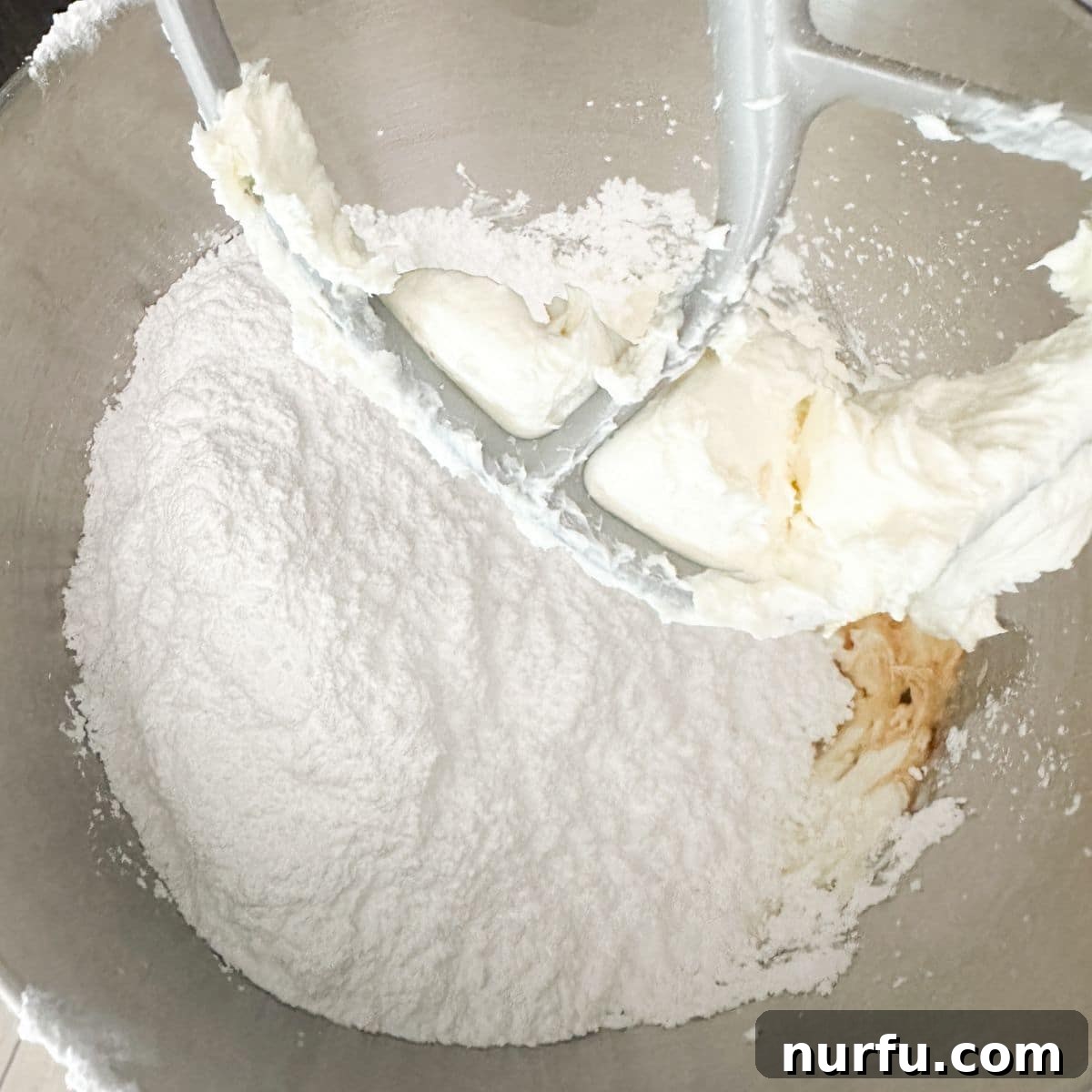 A mixing bowl filled with the creamy mixture of powdered sugar and softened cream cheese, ready to be spread.