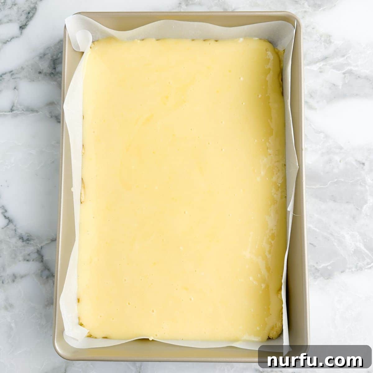 Baking dish with the unbaked chess squares, showing the creamy topping spread over the crust.