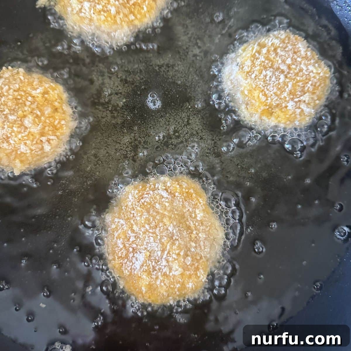 Crispy Golden Chicken Croquettes 9 Several chicken croquettes frying in hot vegetable oil in a large skillet, sizzling and starting to brown.