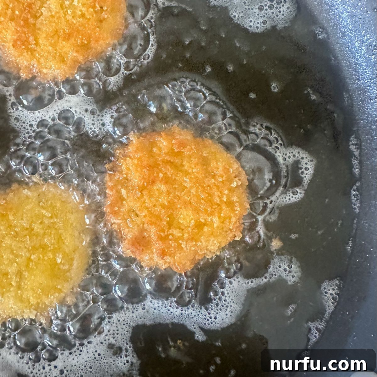 Crispy Golden Chicken Croquettes 10 Perfectly golden-brown chicken croquettes frying in hot oil, almost ready to be removed from the pan.