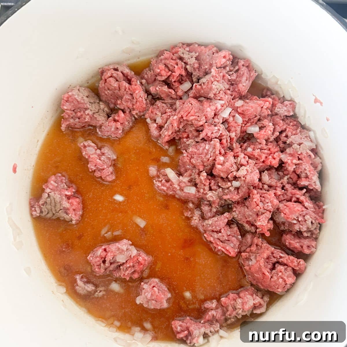 Ultimate Chili Dog Sauce 4 Pot with ground beef and beef broth, being stirred.