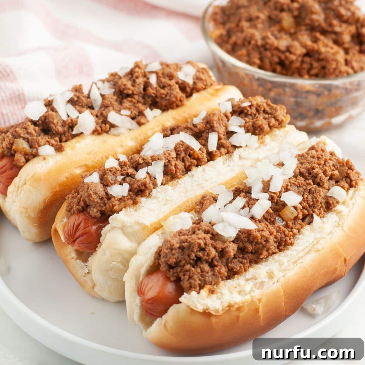 Ultimate Chili Dog Sauce 7 Plate of hot dogs generously topped with homemade chili and garnished with diced onions.