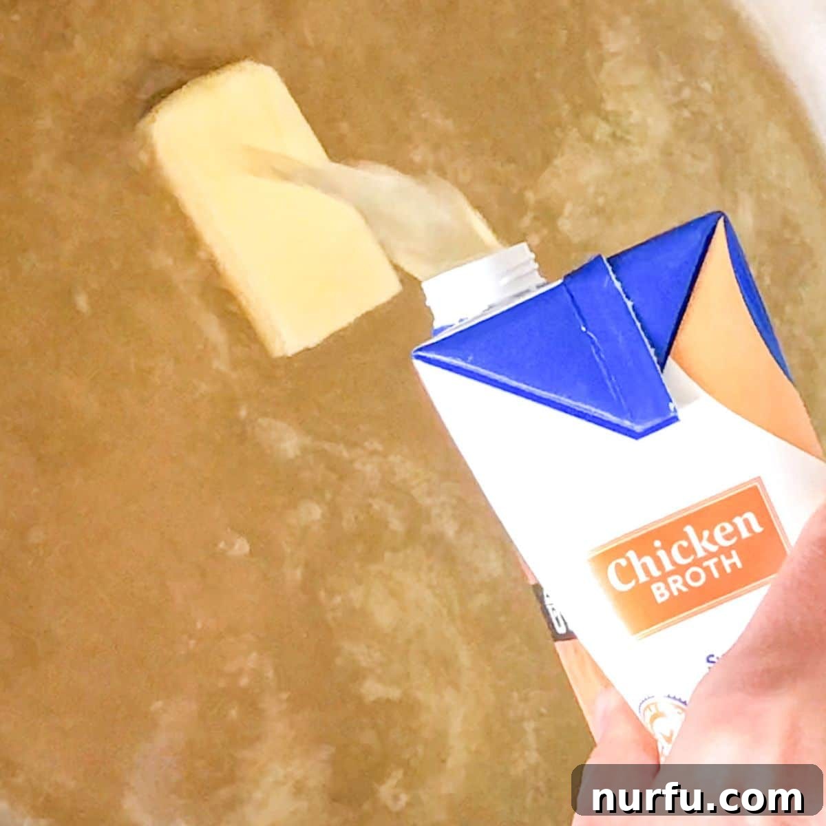 Simply Perfect Buttered Noodles 3 Pouring golden chicken broth into a wide pot with a knob of butter melting at the bottom.