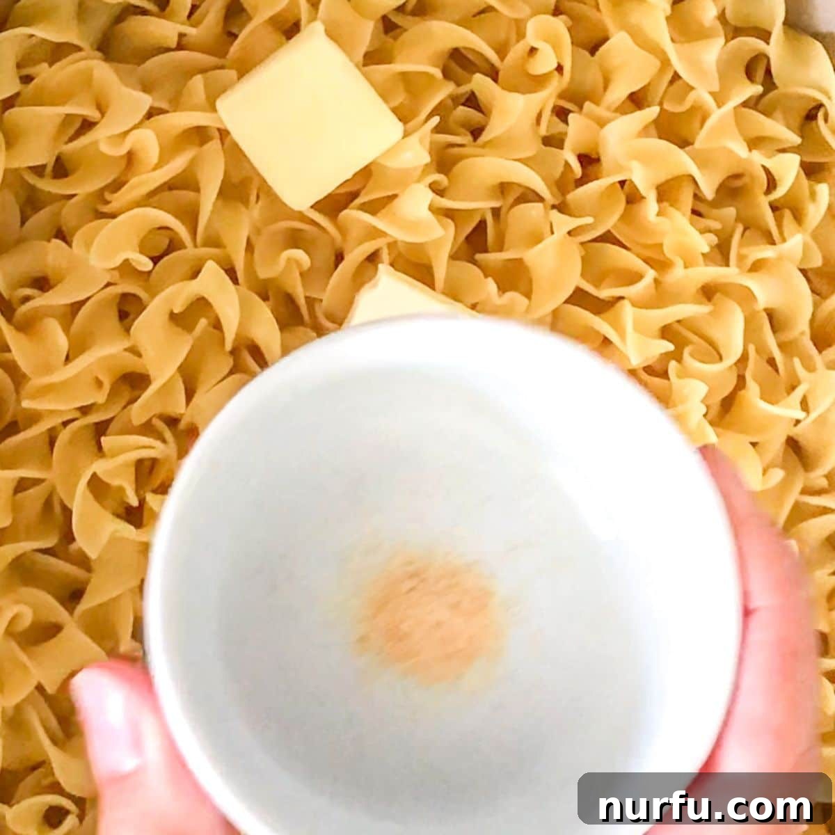 Simply Perfect Buttered Noodles 5 Close-up of cooked egg noodles glistening with melted butter and garlic powder in a skillet.