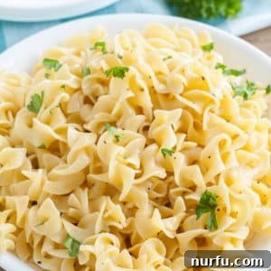 A round white bowl filled with cooked egg noodles, ready to serve.