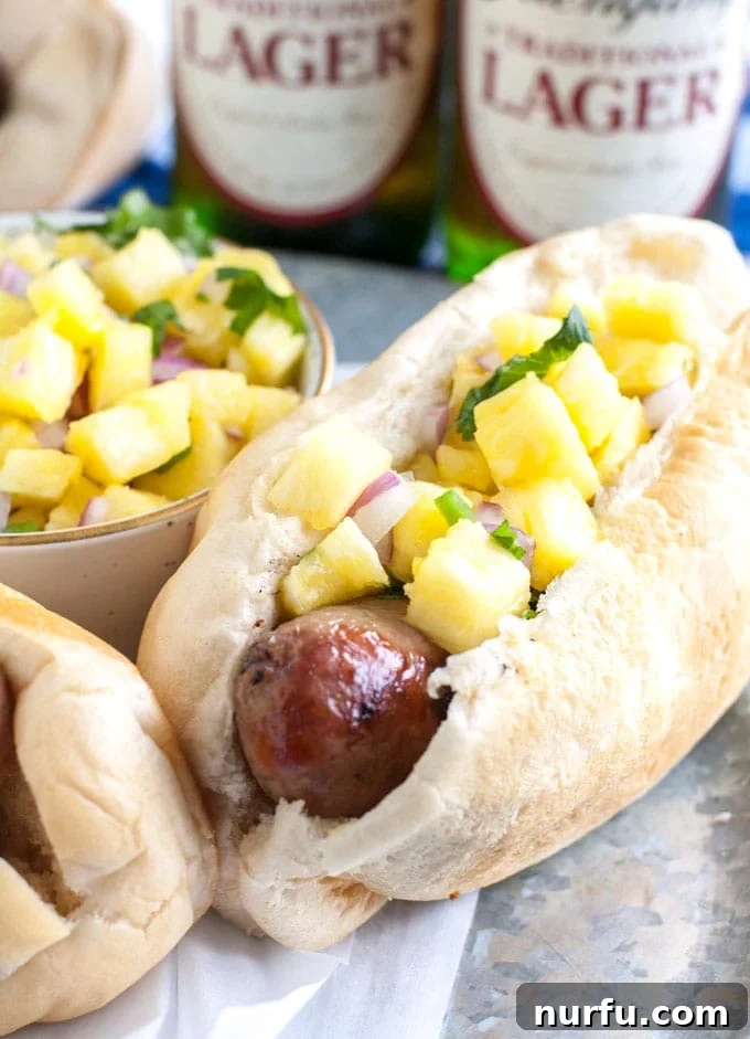 Bratwurst Goes Tropical 2 Grilled Bratwurst with a vibrant pineapple salsa topping, ready for a summer cookout.