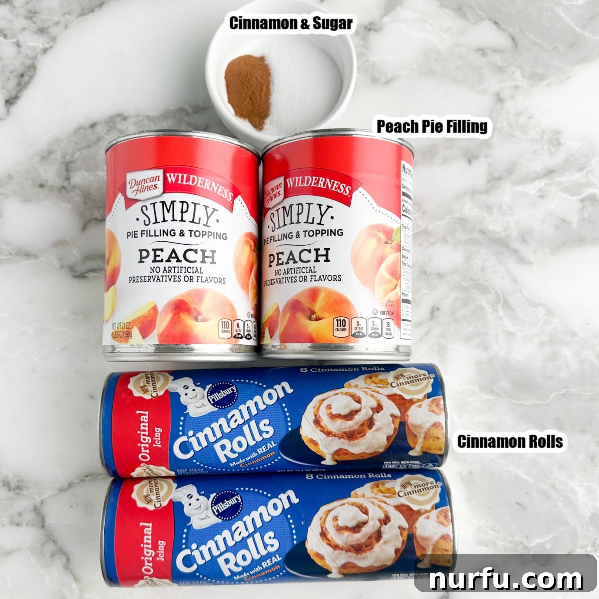 Peachy Cinnamon Swirl Cobbler 3 Ingredients for cinnamon roll peach cobbler: two cans of cinnamon rolls, two cans of peach pie filling, and a small bowl of cinnamon sugar mixture.