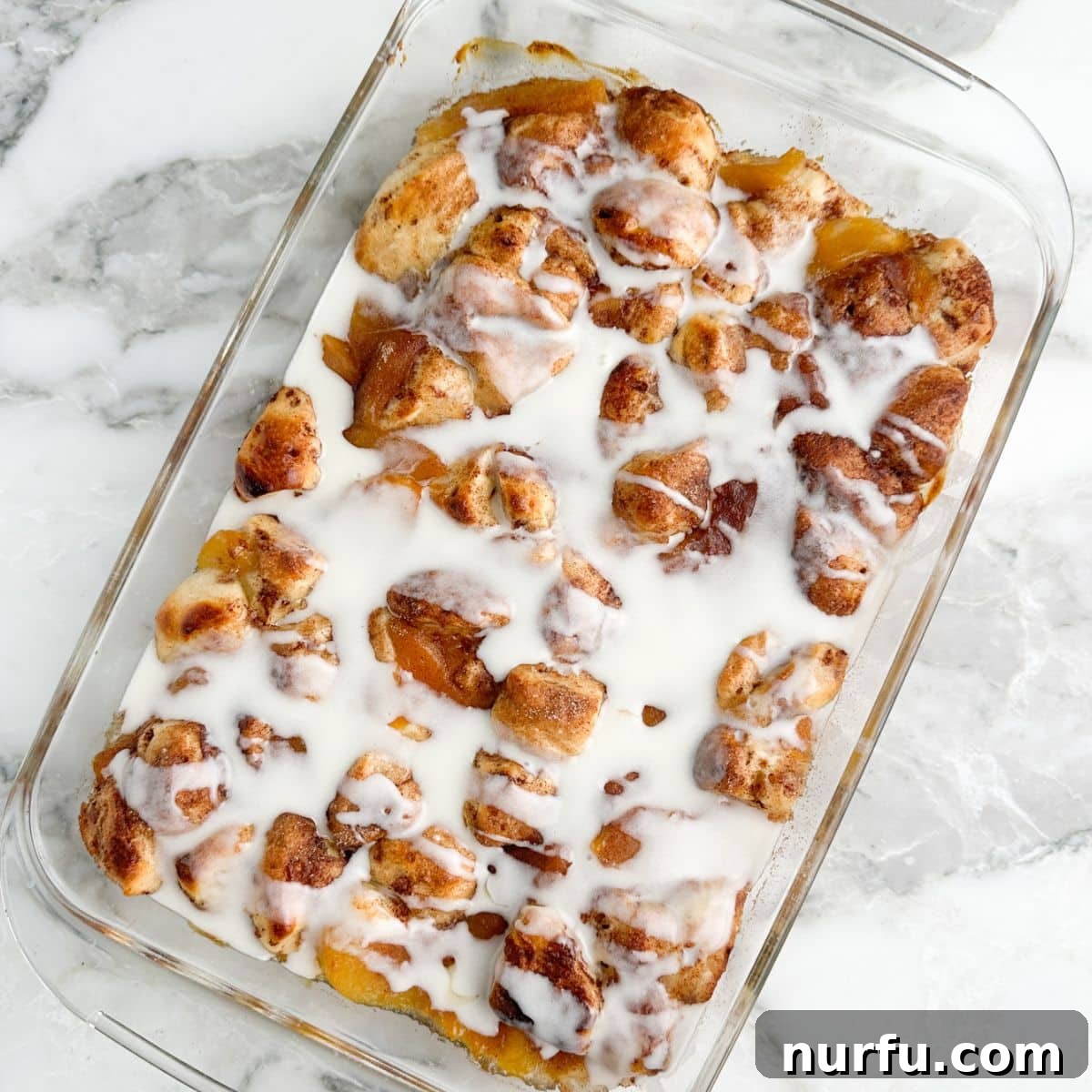 Peachy Cinnamon Swirl Cobbler 9 Freshly baked cinnamon roll peach cobbler with a generous drizzle of white icing on top.