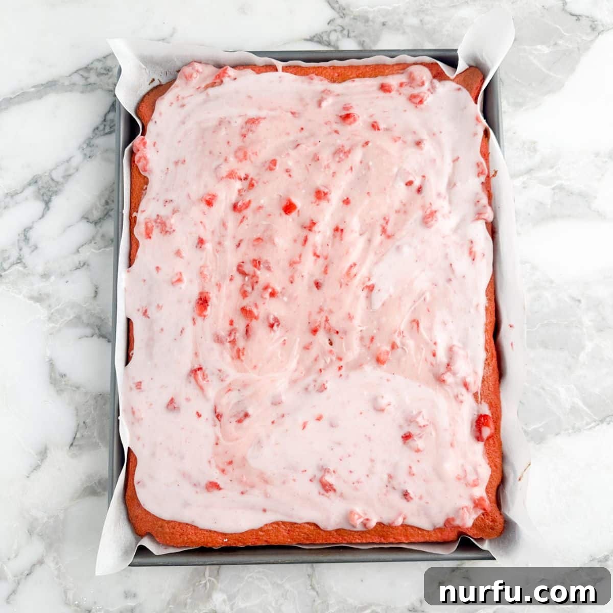 Freshly baked strawberry sheet cake cooling on a wire rack.
