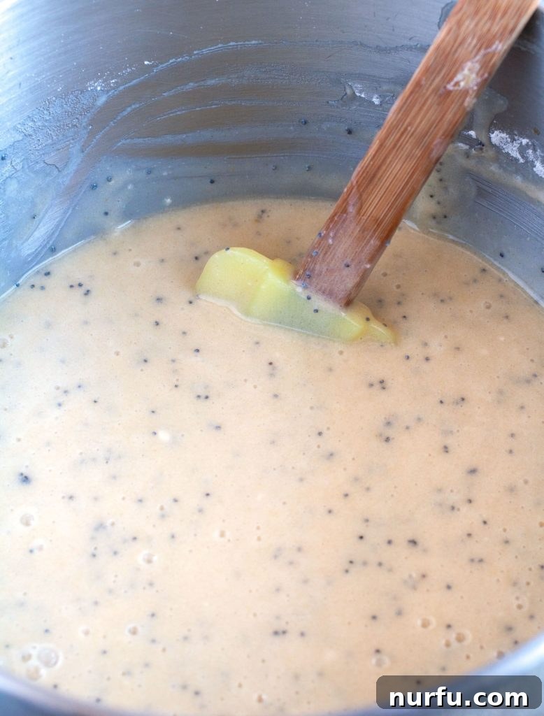 Poppy Seed Cake Batter Cake batter in a mixing bowl with spatula