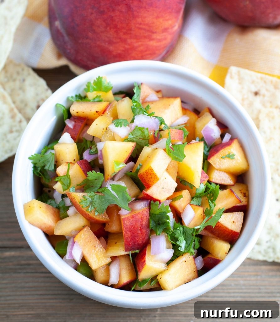 A large bowl filled with freshly prepared, colorful peach salsa, showcasing its irresistible texture and vibrant ingredients.