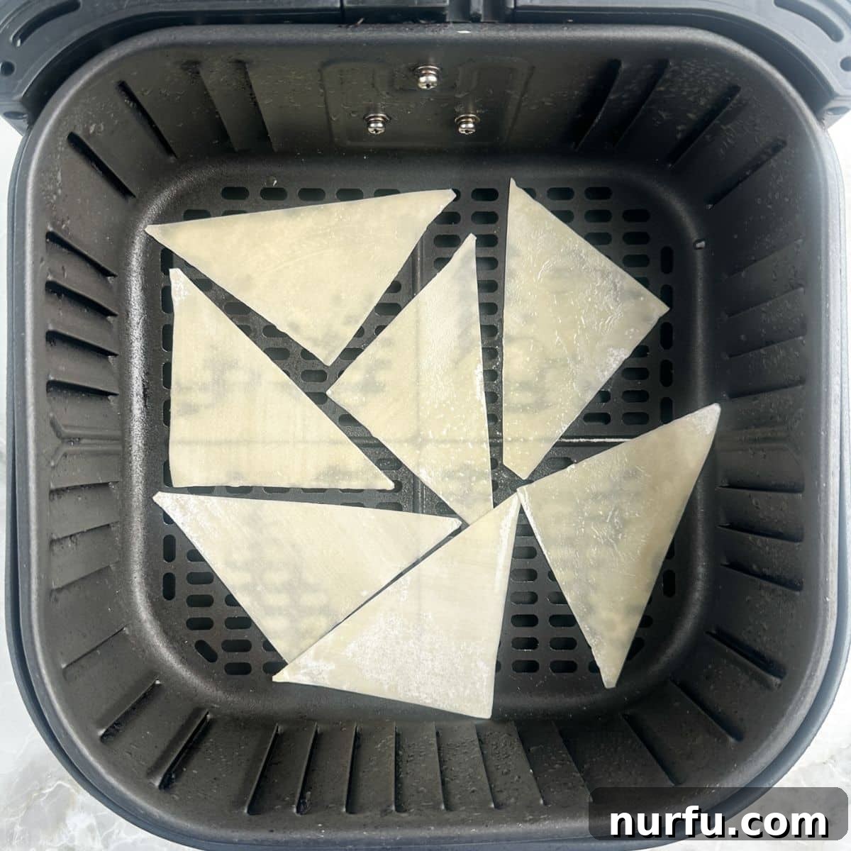 Effortless Air Fryer Wonton Crisps 5 Air fryer basket neatly filled with uncooked wonton wrappers in a single layer.