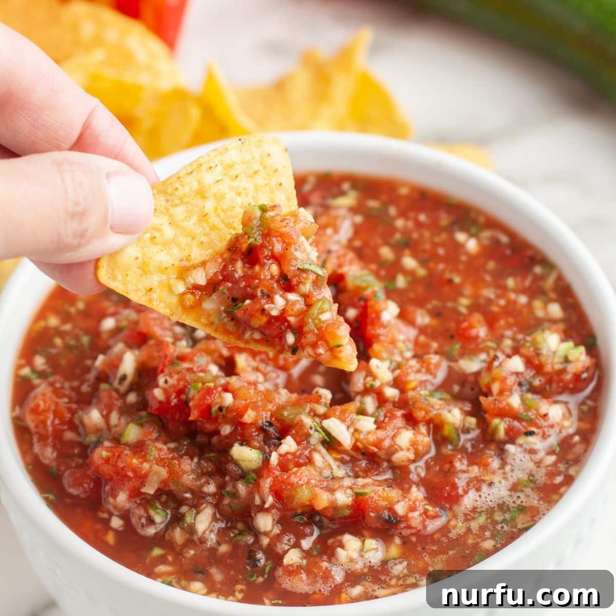 Zesty Zucchini Salsa 2 A vibrant bowl of homemade zucchini salsa, garnished with fresh cilantro and lime wedges, surrounded by crispy tortilla chips, perfect for a summer snack or appetizer.
