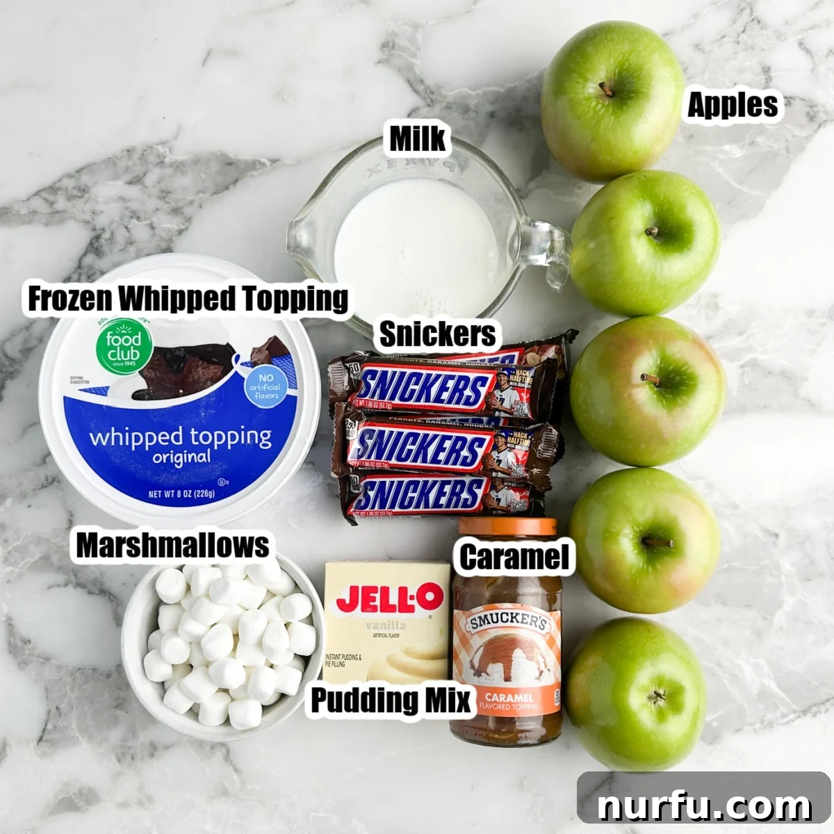 Snickers Caramel Apple Dream 3 Collection of key ingredients for Snickers Caramel Apple Salad: green apples, milk, Snickers candy bars, caramel sauce, instant pudding mix, mini marshmallows, and whipped topping.