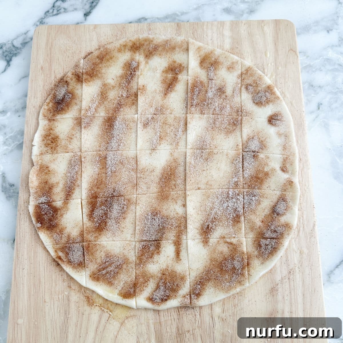 Pie crust with cinnamon and sugar, neatly cut into uniform squares on a baking sheet, pre-baking.