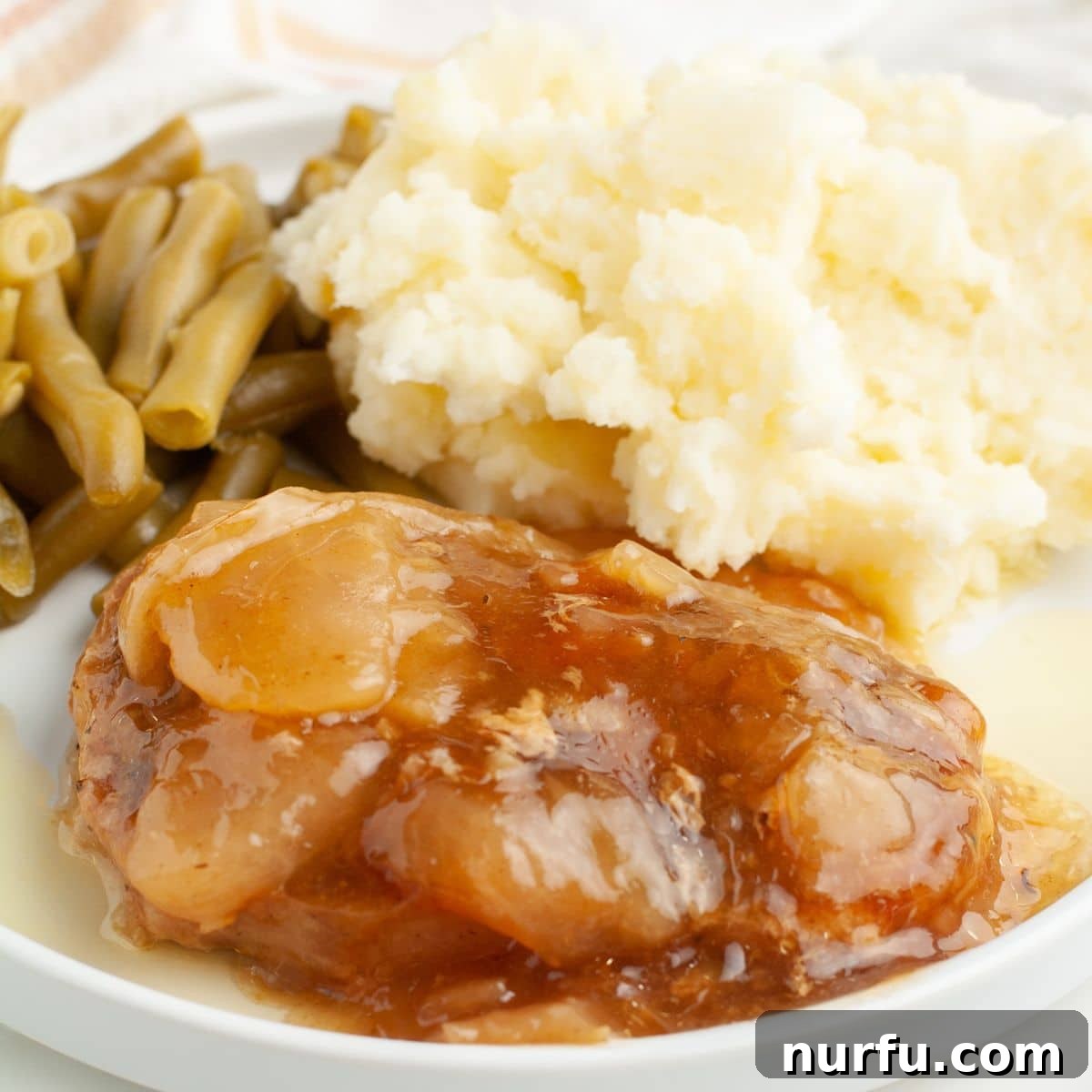 Tender Slow Cooker Pork and Apples 2 Plate with succulent apple pie pork chop, creamy mashed potatoes, and vibrant green beans, ready to be enjoyed.