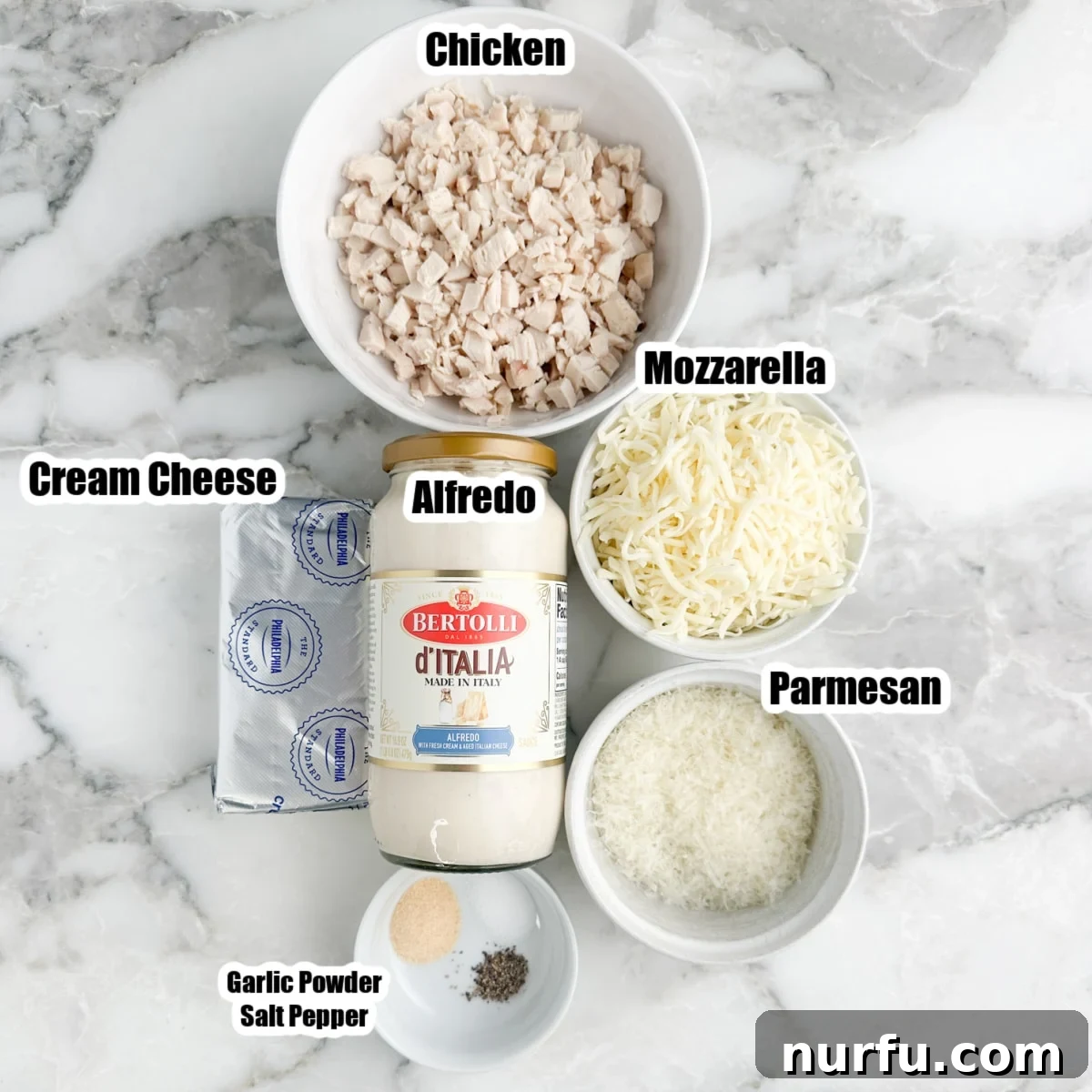 Ultimate Chicken Alfredo Dip 3 Bowl of shredded rotisserie chicken, a jar of Alfredo sauce, blocks of cream cheese, shredded mozzarella, grated parmesan, and seasonings arranged on a wooden board.