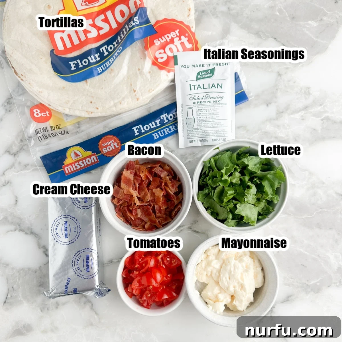 Creamy BLT Roll-Ups 3 A vibrant display of fresh ingredients for BLT pinwheels including large flour tortillas, a block of cream cheese, crisp lettuce, cooked bacon, ripe tomatoes, and mayonnaise.