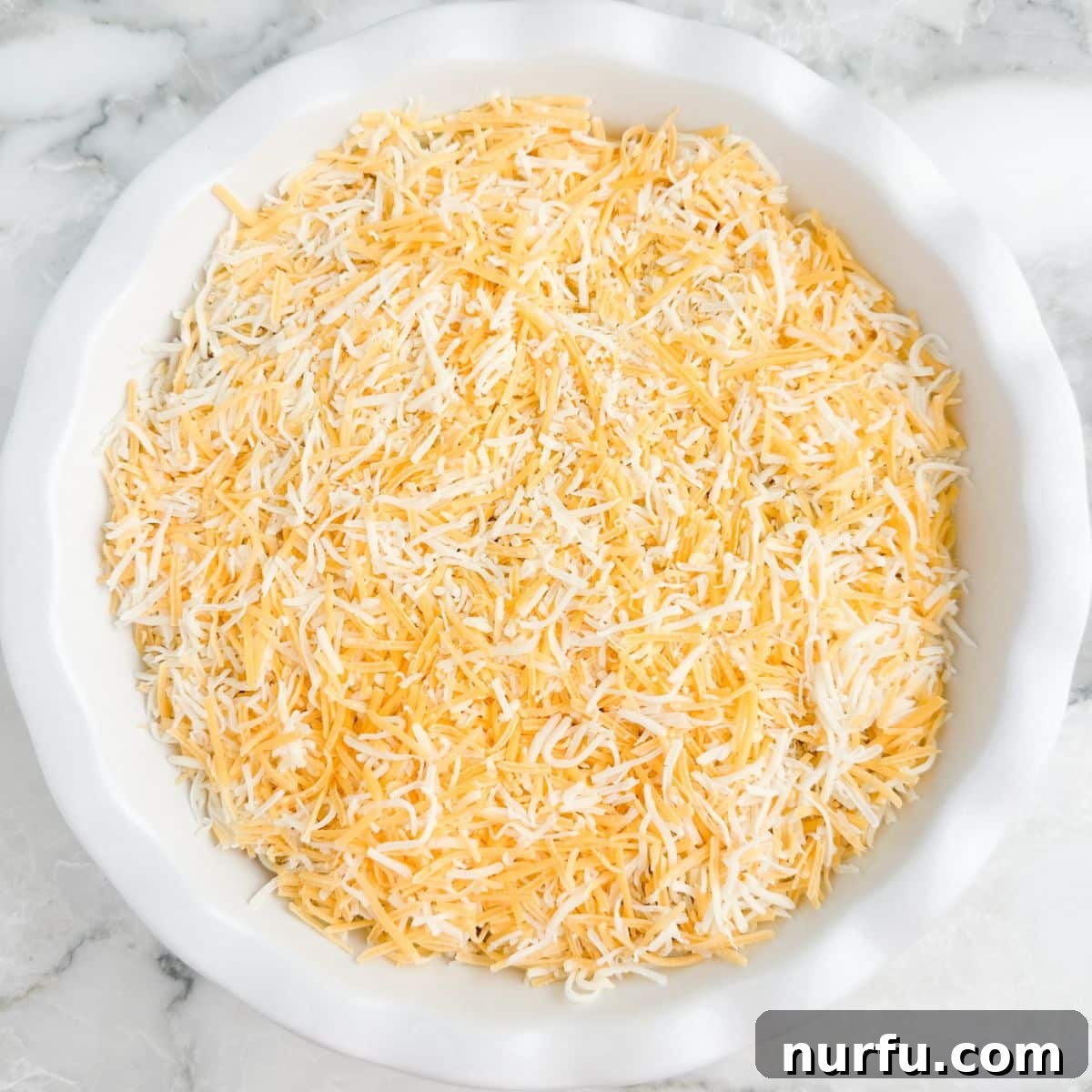 Stacked Salsa Sensation 7 The layered dip in a pie dish, now fully topped with a generous layer of shredded cheese, ready to be served or chilled.