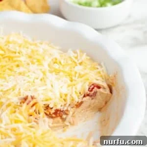 Pie dish with layered salsa dip that is topped with cheese.
