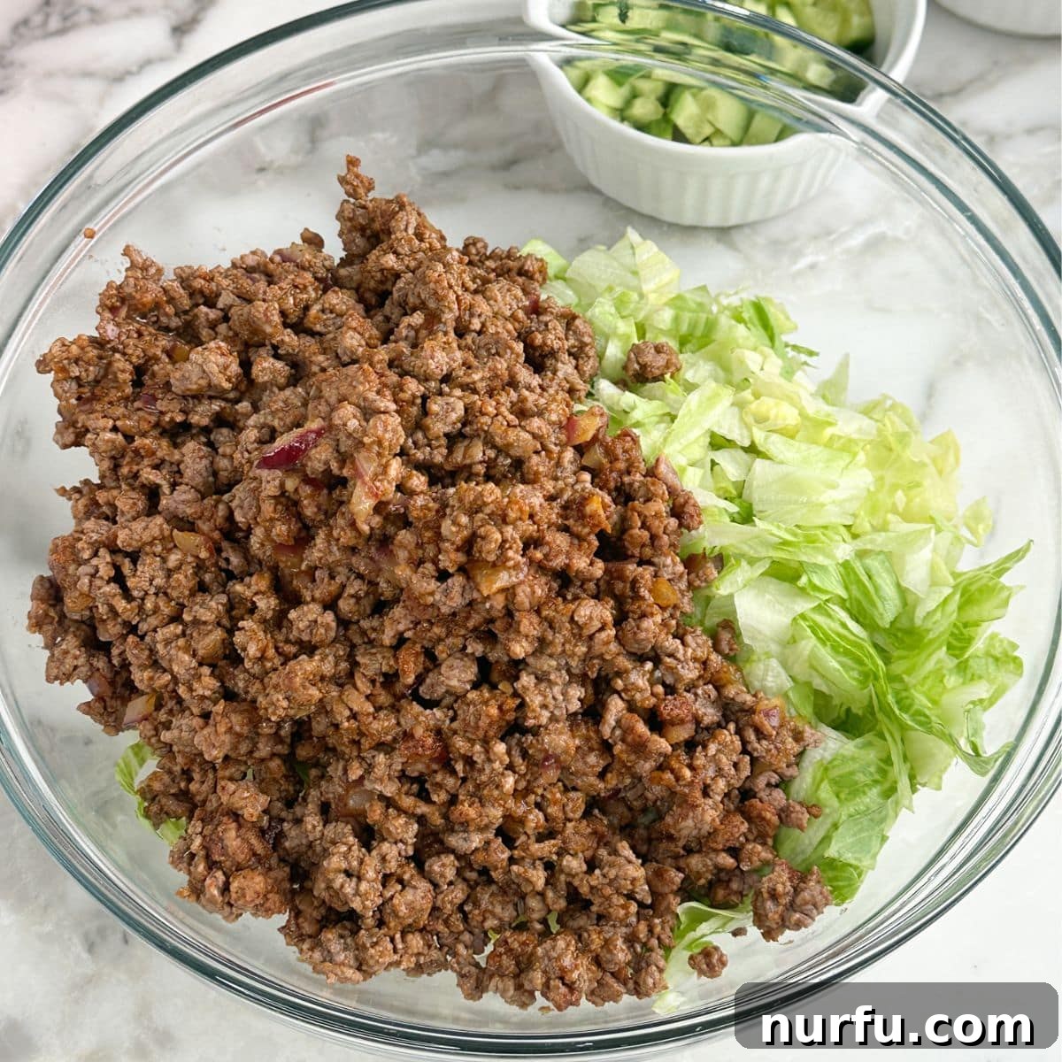 Catalina Kicked Taco Salad 6 Large bowl with a layer of chopped lettuce topped with cooked ground beef.