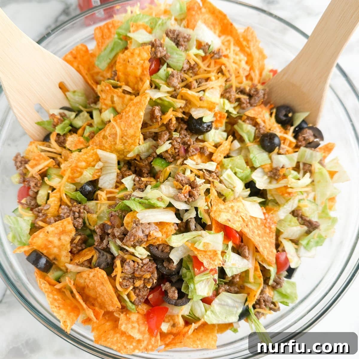 Catalina Kicked Taco Salad 9 Bowl of colorful Dorito taco salad with serving spoons.