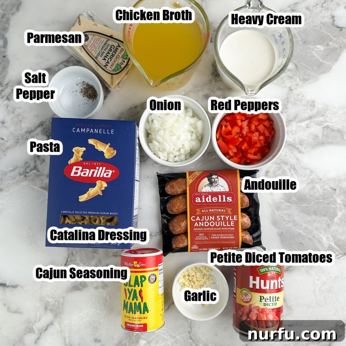 Collection of fresh ingredients for Cajun sausage pasta: a box of pasta, Cajun seasoning blend, canned diced tomatoes, rich chicken broth, heavy cream, fresh onions, colorful bell peppers, and smoky andouille sausage.
