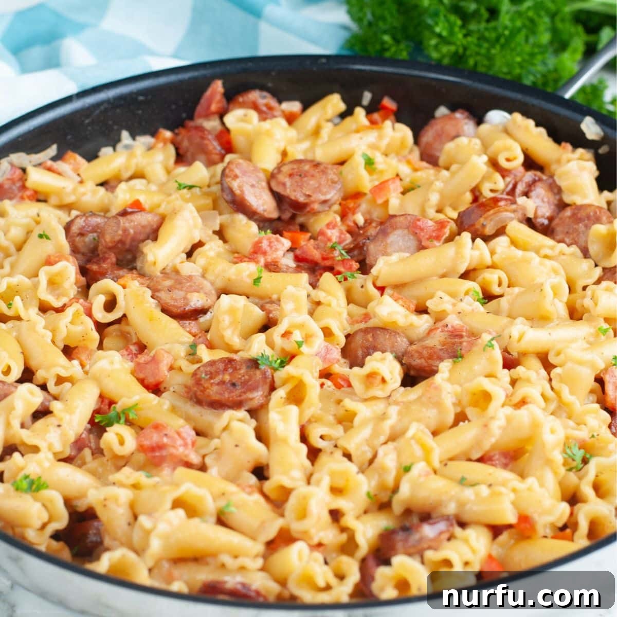 A large skillet overflowing with the finished Cajun sausage pasta, steaming and ready to be served, highlighting its rich, creamy texture and hearty ingredients.