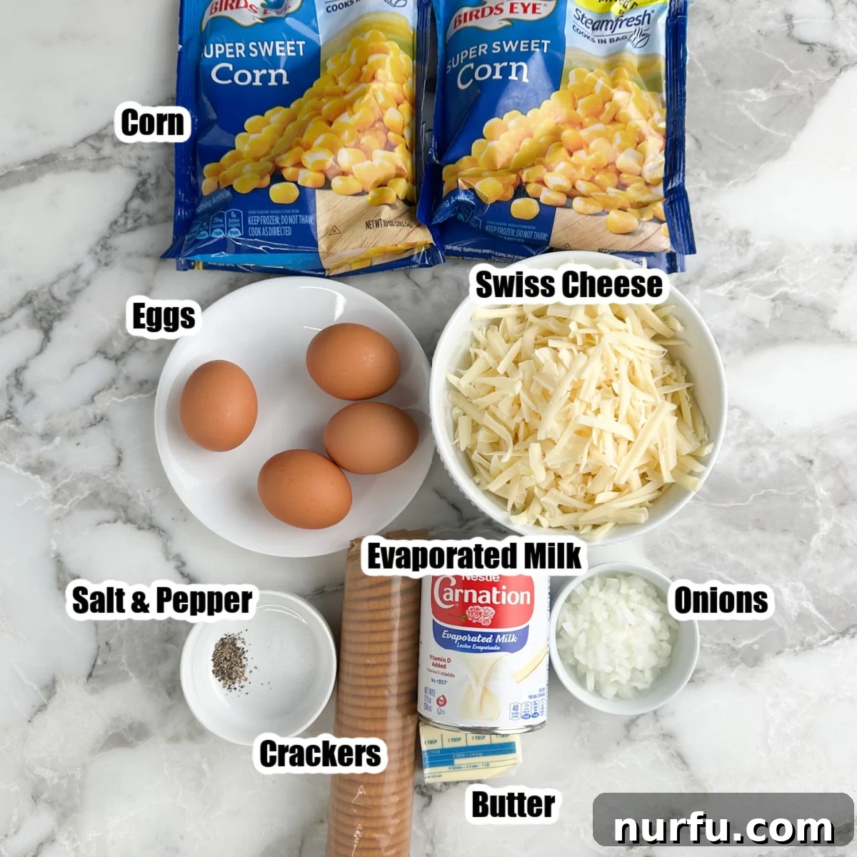 Creamy Swiss Corn Gratin 3 Individual ingredients laid out: bags of frozen corn, fresh eggs, shredded Swiss cheese, a sleeve of Ritz crackers, a can of evaporated milk, a whole onion, and a stick of butter.