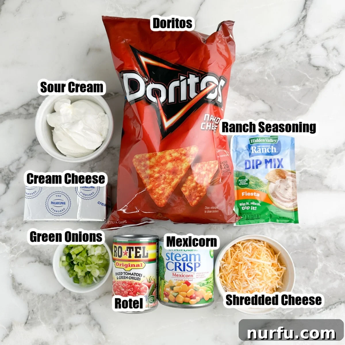 A spread of ingredients: bag of Doritos, ranch seasoning, bowl of sour cream, shredded cheese, green onions, Mexicorn, and Rotel.