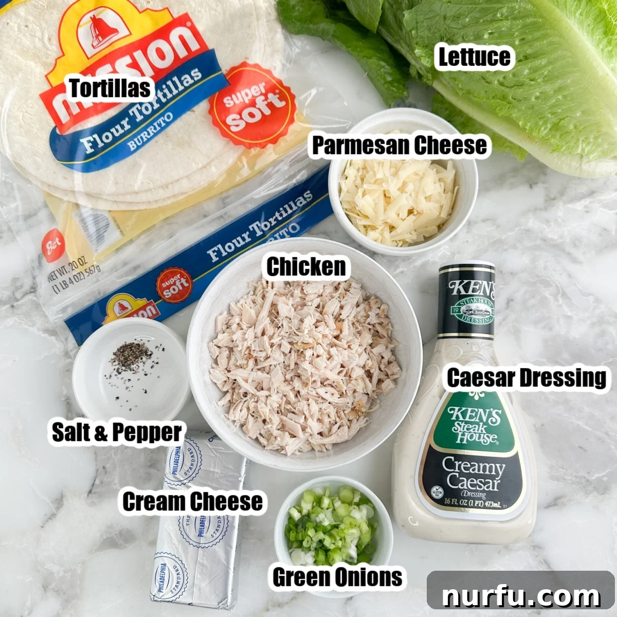 Bowls of shredded chicken, chopped green onions, grated Parmesan cheese, a bottle of Caesar dressing, and fresh romaine lettuce, ready for pinwheel assembly.