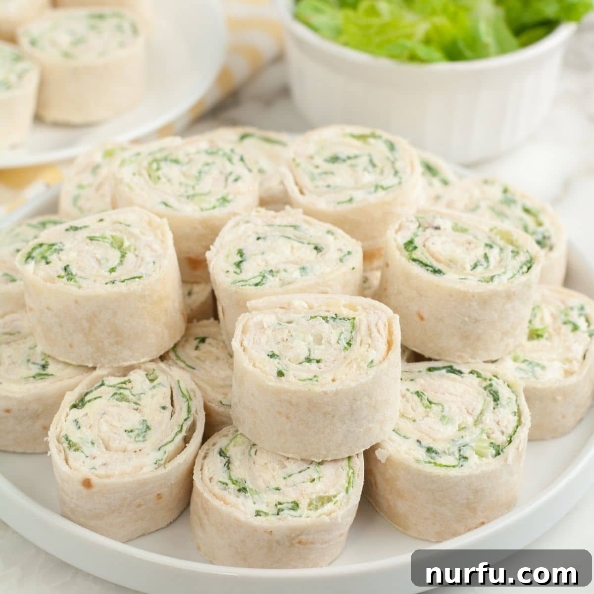 A vibrant plate of chicken Caesar pinwheels, artfully arranged and ready to be served, garnished with fresh herbs.