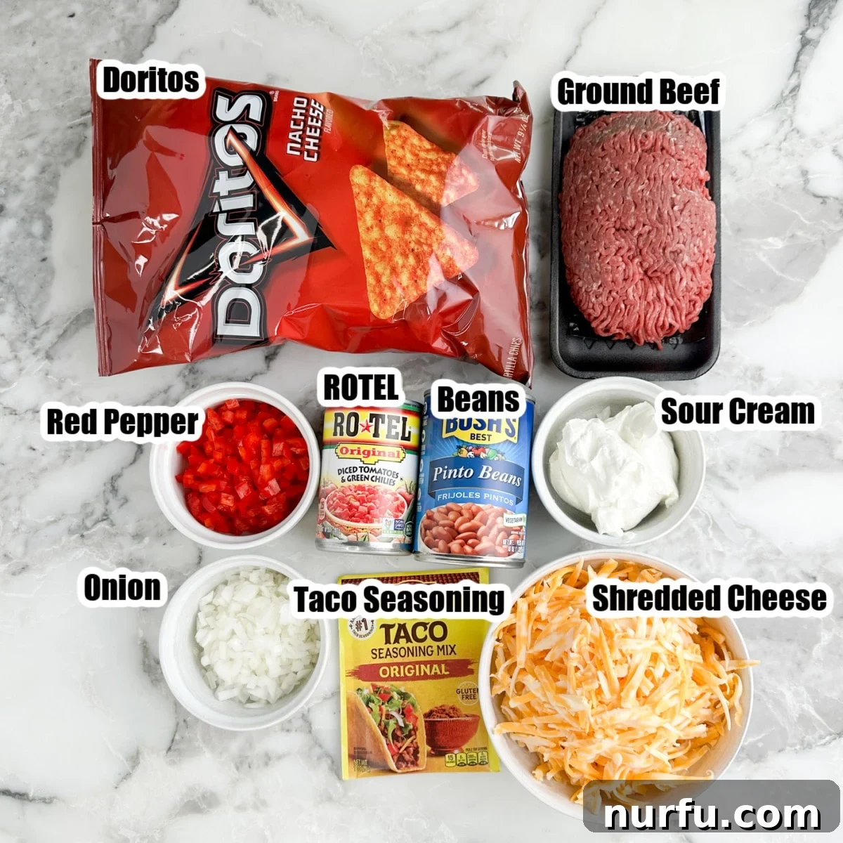 Assortment of Doritos, ground beef, canned beans, Rotel, sour cream, cheese, peppers, onions, and taco seasoning.