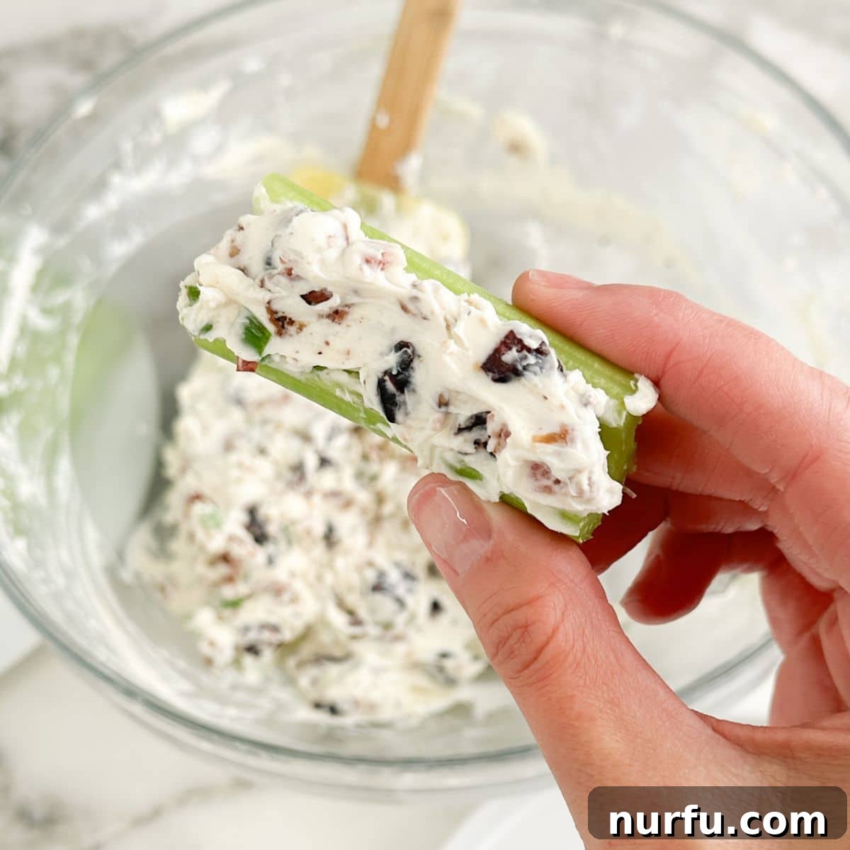 Creamy Celery Crunch 7 A hand holding a perfectly prepared stalk of cream cheese stuffed celery, showcasing the generous filling and crisp texture.