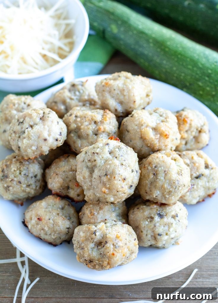 Close-up of Parmesan Pesto Meatballs garnished with fresh Parmesan cheese on a plate.