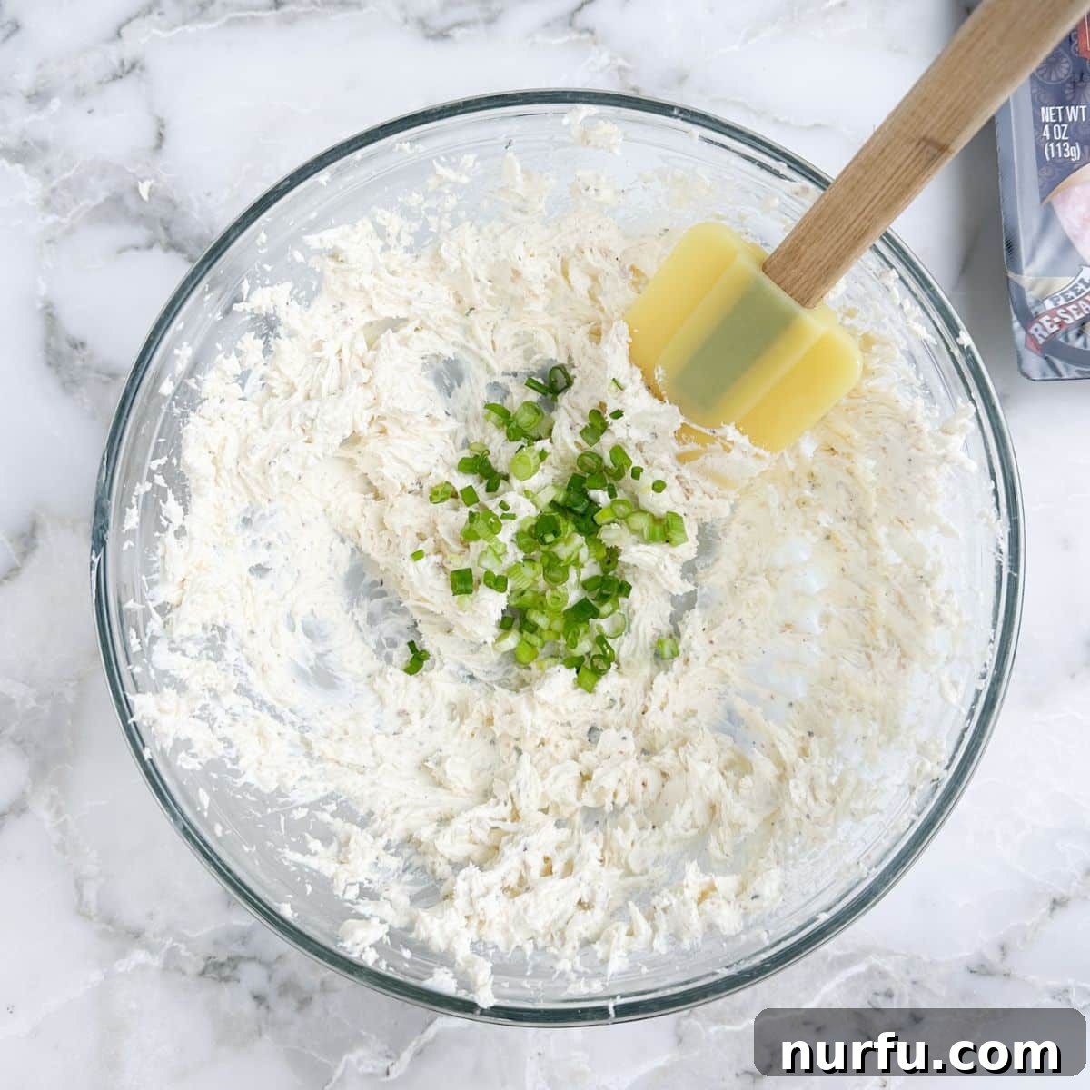 Savory Salami Bites 5 Bowl of cream cheese mixture with diced green onions being stirred in.