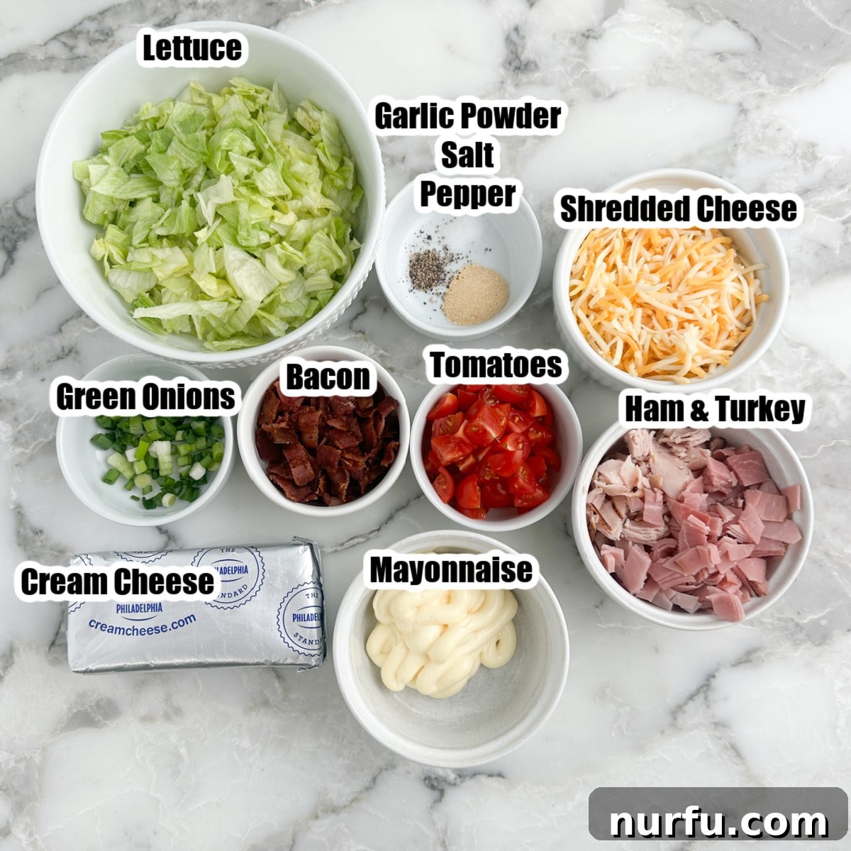 Bowl of chopped lettuce, tomato, green onions, shredded cheese, mayonnaise, bacon, seasonings, and cream cheese for club sandwich dip. 