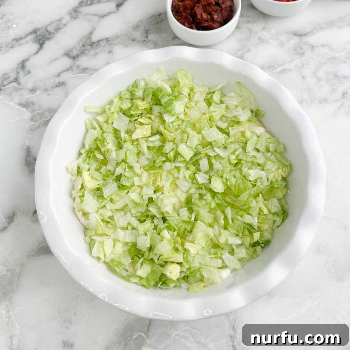 Serving dish with creamy base topped with a layer of chopped lettuce.