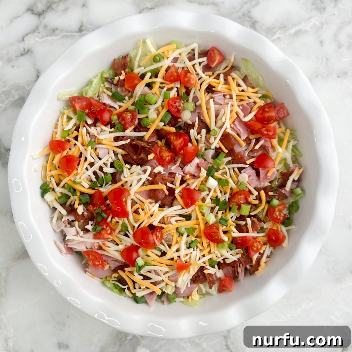 Fully assembled club sandwich dip in a serving dish, showcasing all the delicious layers.