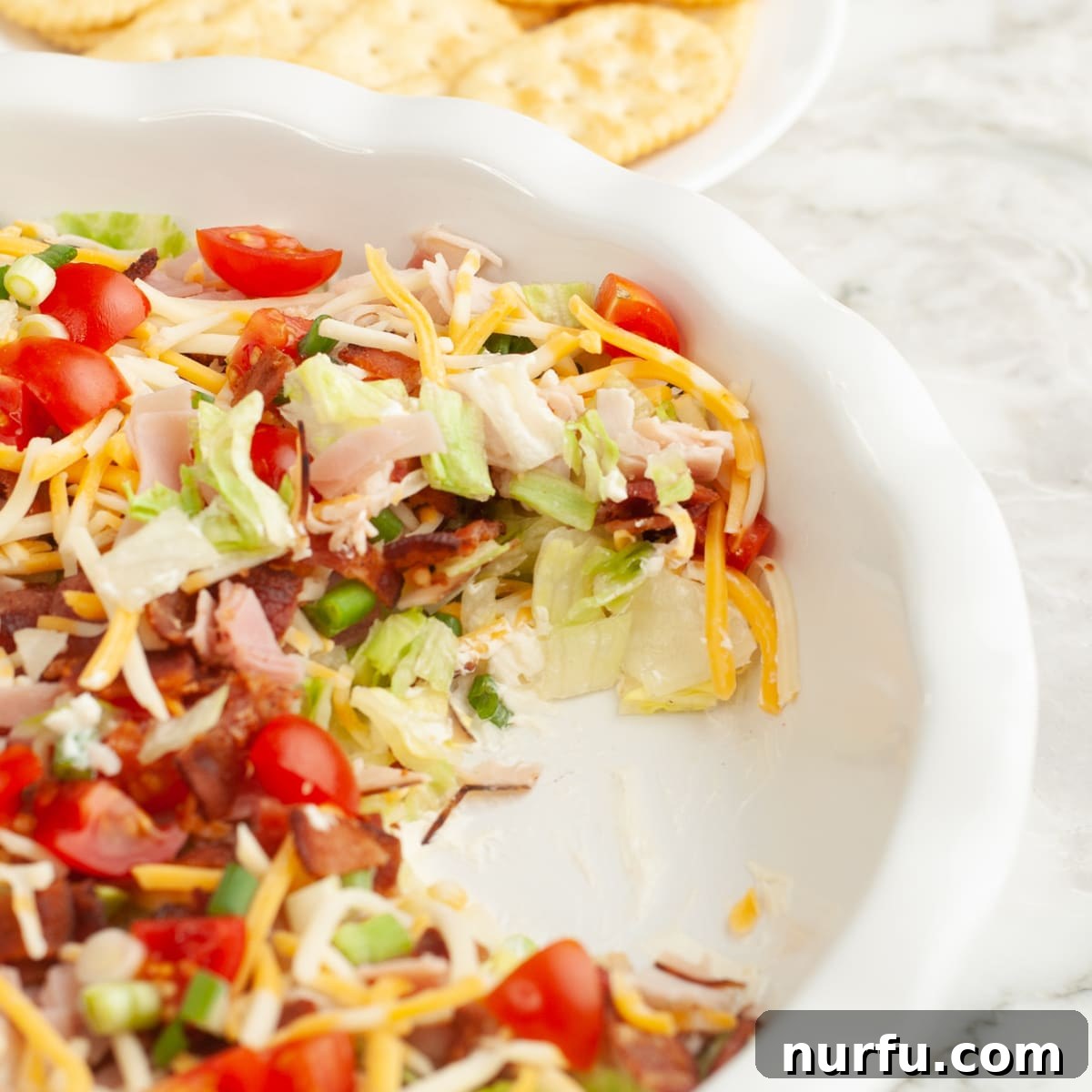 Baking dish with club sandwich dip, showcasing its layered goodness. 