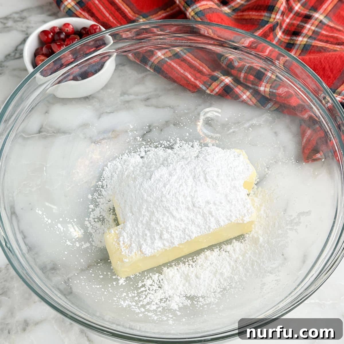 Zesty Cranberry Compound 5 A large mixing bowl containing softened butter, powdered sugar, and a pinch of salt, being whipped to a creamy consistency with an electric hand mixer.